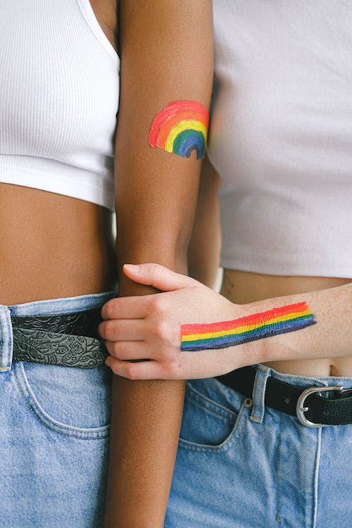 Individuals proudly displaying LGBTQIA+ pride body paint, symbolizing allyship and support for the community.