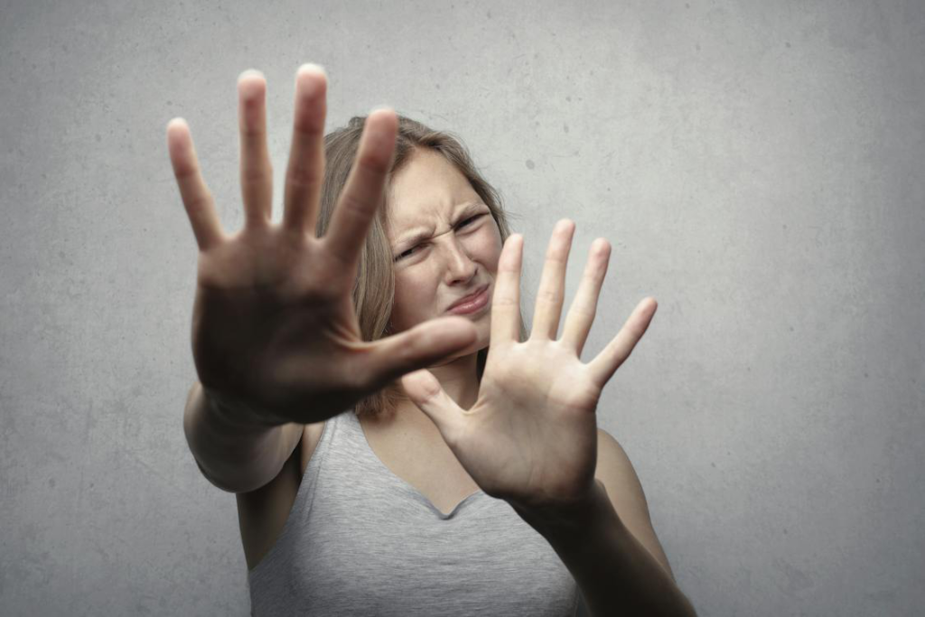 A woman in a gray tank top looking frightened, portraying the emotional struggle associated with imposter syndrome and hidden challenges.