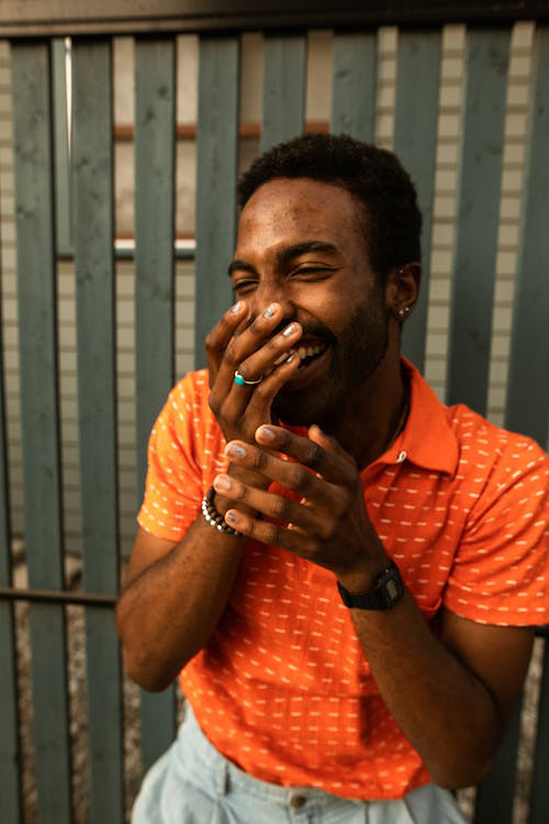 A person is wearing an orange shirt and smiling