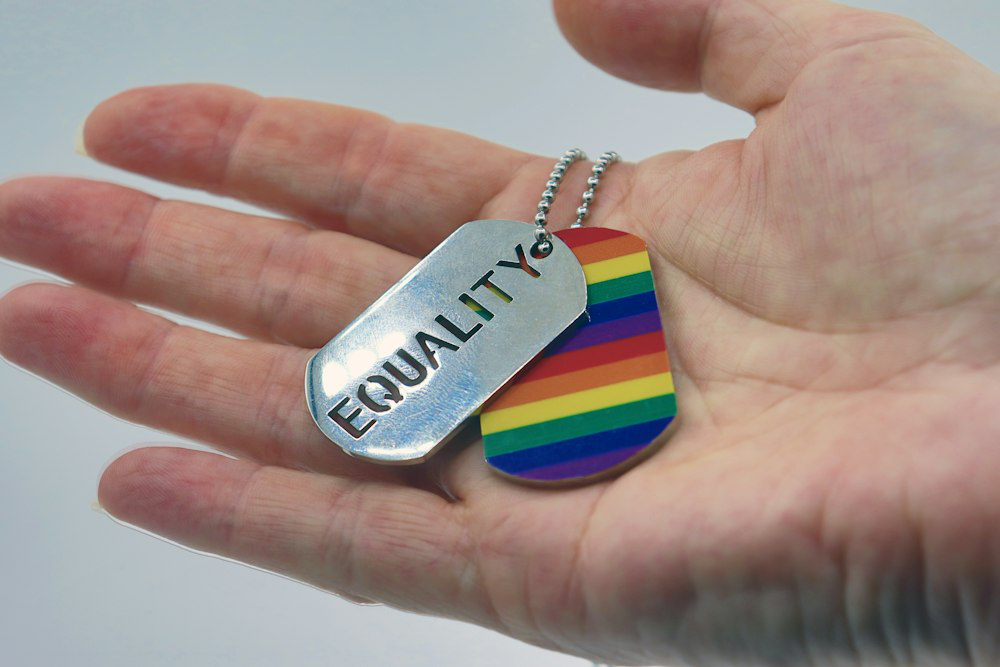A person holding a rainbow tag in their hand, symbolizing LGBTQIA pride and authenticity.