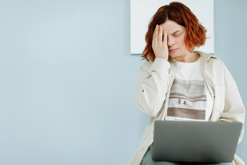 A woman holding her hand on her forehead, depicting the stress and fear associated with imposter syndrome and the fear of failure.