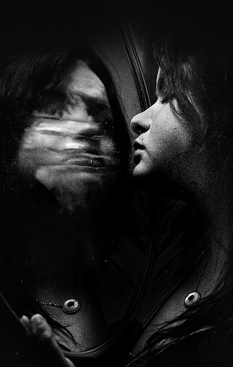 A woman with closed eyes reflecting in a wet mirror, symbolizing self-discovery and the journey toward authenticity.