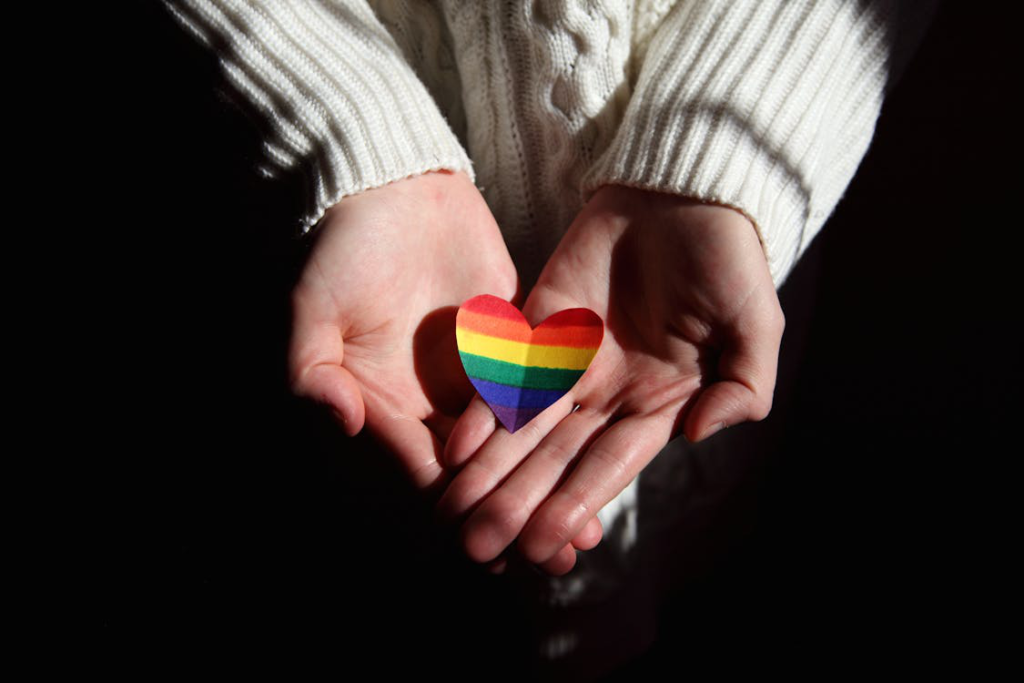 A person holding a colorful heart-shaped object in their hands.