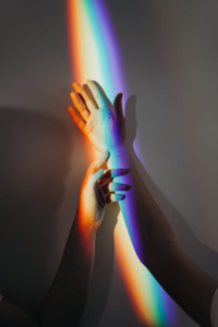 Close-up photo of two hands painted in different colors of the rainbow.